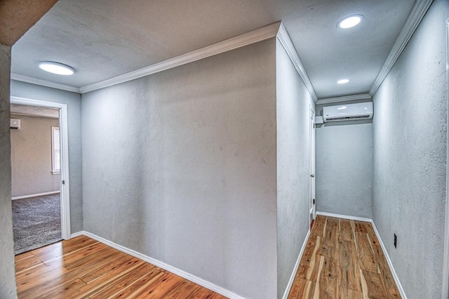 hallway with wood-type flooring, ornamental molding, and a wall mounted AC