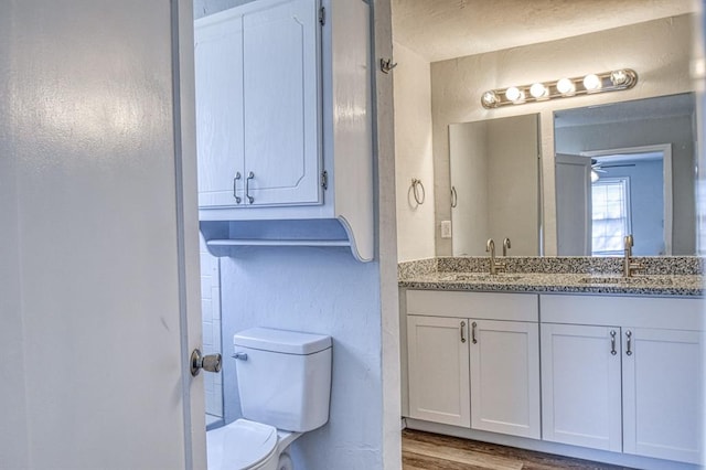 bathroom featuring hardwood / wood-style floors, vanity, toilet, and ceiling fan