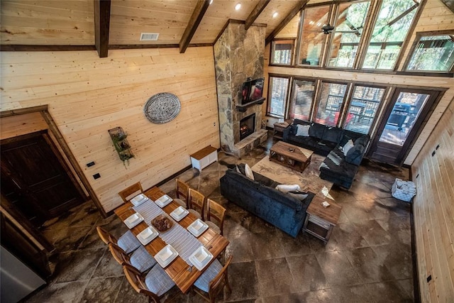 living room with a fireplace, beam ceiling, wood walls, wooden ceiling, and high vaulted ceiling