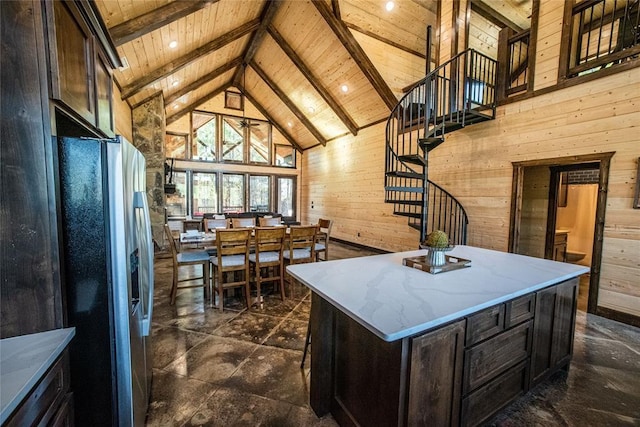 kitchen featuring wood ceiling, stainless steel fridge with ice dispenser, wood walls, and a center island