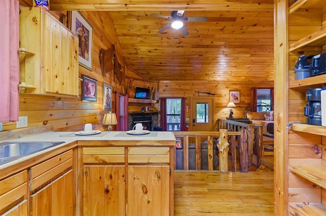 kitchen with wooden ceiling, light hardwood / wood-style flooring, kitchen peninsula, wood walls, and a fireplace