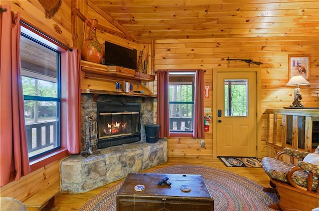 living room featuring hardwood / wood-style floors, lofted ceiling, a stone fireplace, wooden walls, and wood ceiling