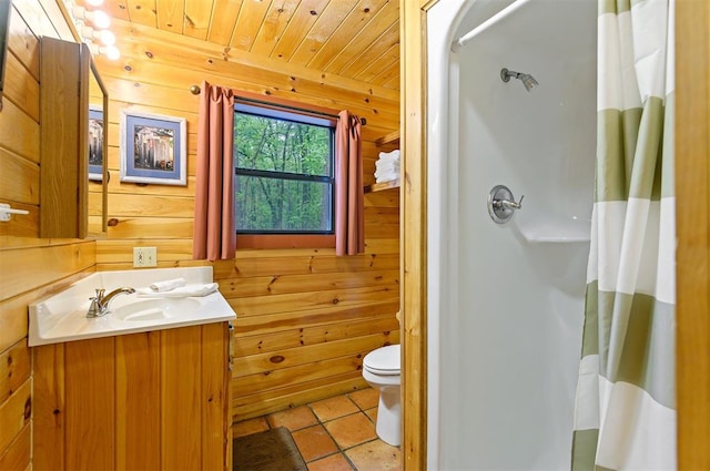 bathroom featuring vanity, wood walls, wooden ceiling, tile patterned floors, and toilet