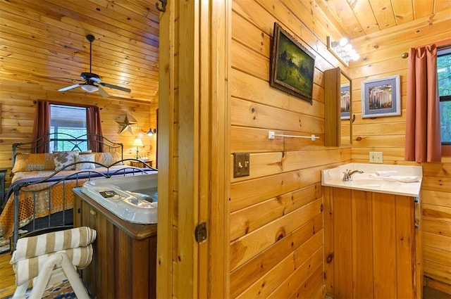 bathroom featuring ceiling fan, vanity, wooden ceiling, and wooden walls