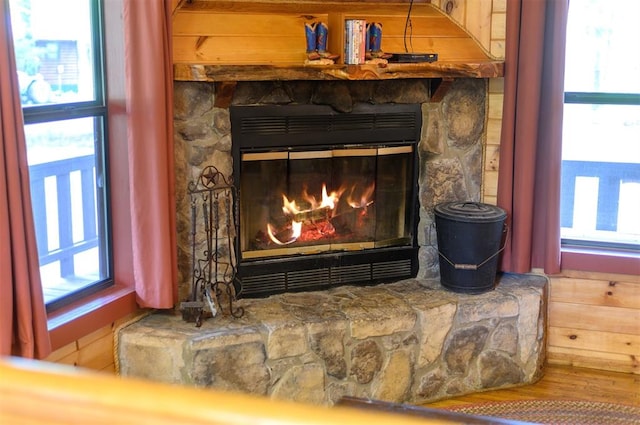 room details with hardwood / wood-style flooring, wood walls, and a stone fireplace