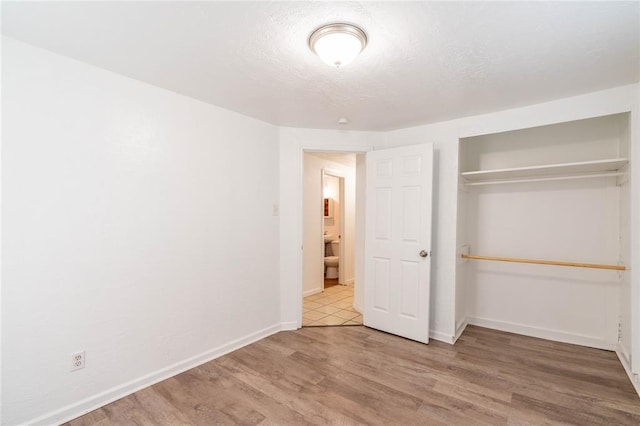 unfurnished bedroom with a closet and light wood-type flooring