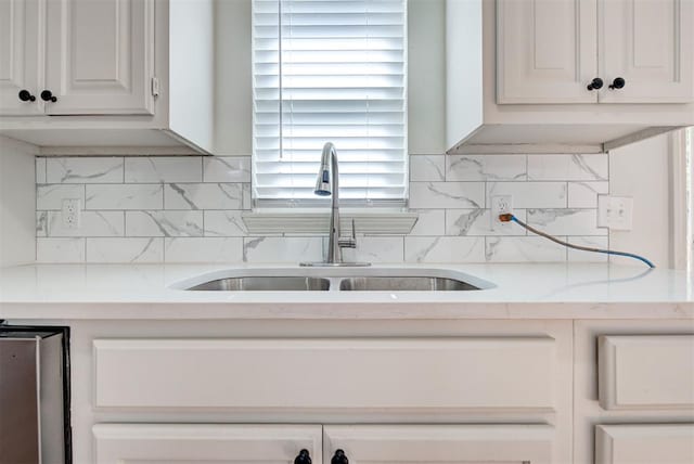 kitchen with decorative backsplash, white cabinetry, sink, and light stone countertops