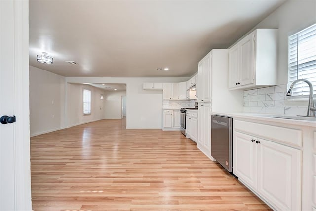 kitchen featuring white cabinets, decorative backsplash, light hardwood / wood-style floors, and appliances with stainless steel finishes