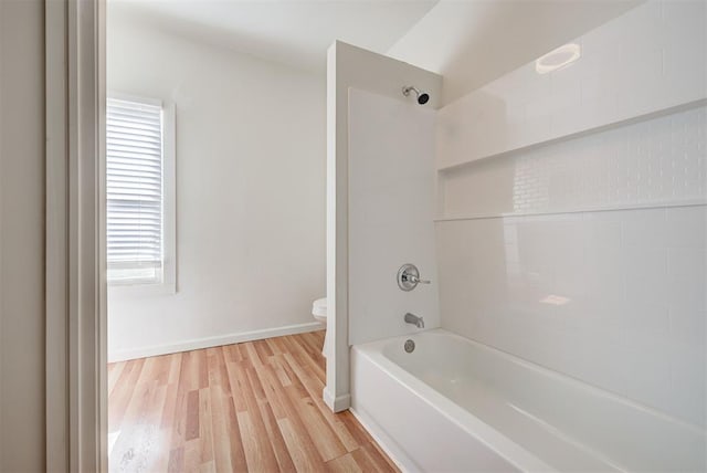 bathroom with hardwood / wood-style floors, toilet, and tub / shower combination