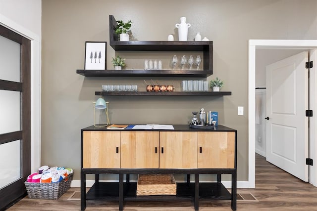 bar with light brown cabinetry and dark hardwood / wood-style floors