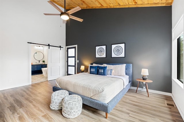 bedroom featuring a barn door, high vaulted ceiling, wood ceiling, and light hardwood / wood-style floors