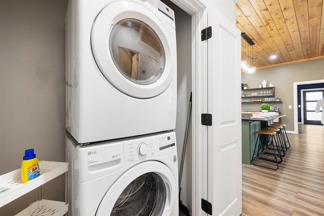 laundry room featuring light hardwood / wood-style floors, wooden ceiling, and stacked washer / dryer