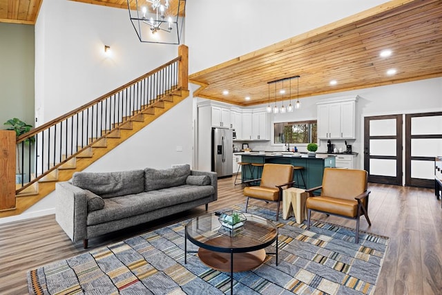 living room with hardwood / wood-style flooring, an inviting chandelier, wooden ceiling, and sink