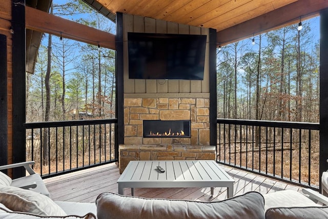 wooden terrace featuring an outdoor stone fireplace