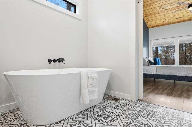 bathroom featuring hardwood / wood-style floors, a washtub, a healthy amount of sunlight, and lofted ceiling