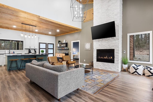 living room featuring a fireplace, a high ceiling, dark hardwood / wood-style flooring, and wooden ceiling