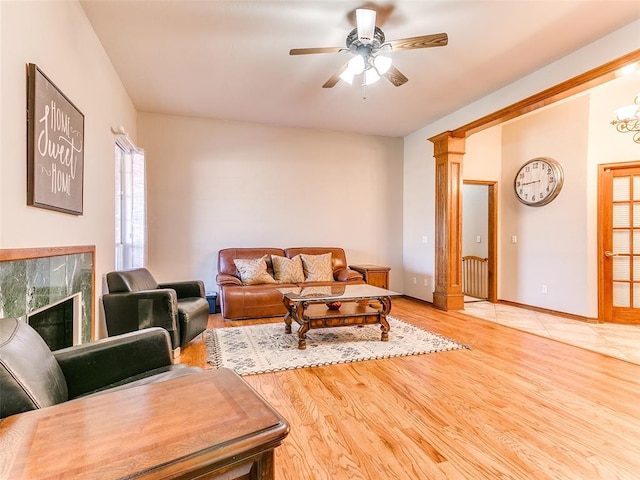 living room featuring ceiling fan, wood-type flooring, and a tile fireplace