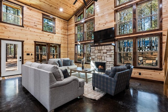 living room featuring wooden walls, wooden ceiling, a fireplace, and high vaulted ceiling