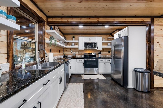 kitchen with wood ceiling, stainless steel appliances, sink, white cabinetry, and wood walls