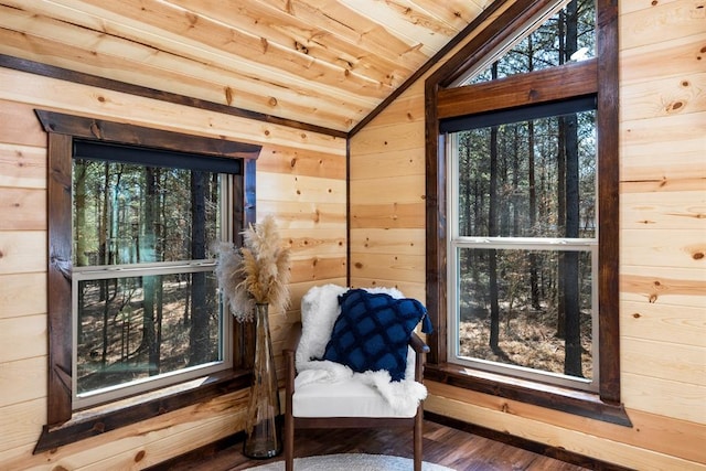 living area with hardwood / wood-style flooring, vaulted ceiling, plenty of natural light, and wood walls