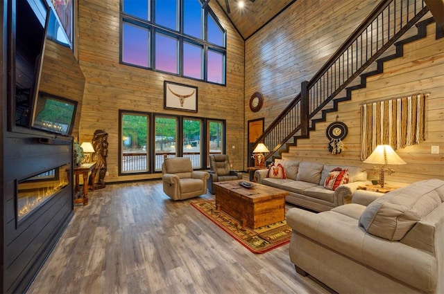 living room featuring wood walls, hardwood / wood-style floors, and high vaulted ceiling