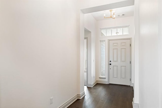 entrance foyer featuring an inviting chandelier and dark wood-type flooring