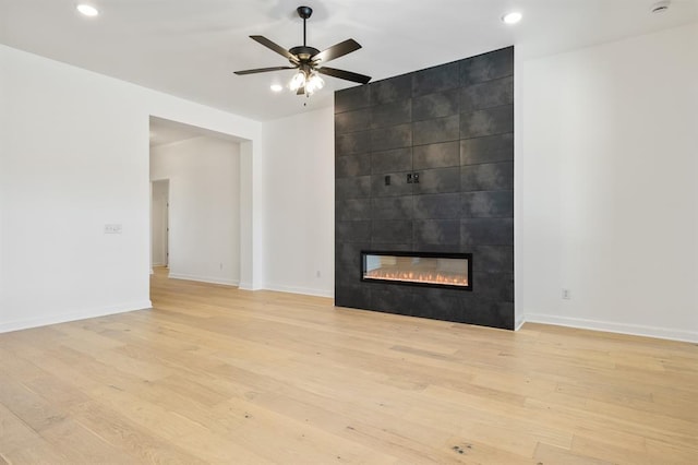 unfurnished living room with light hardwood / wood-style floors, ceiling fan, and a tiled fireplace