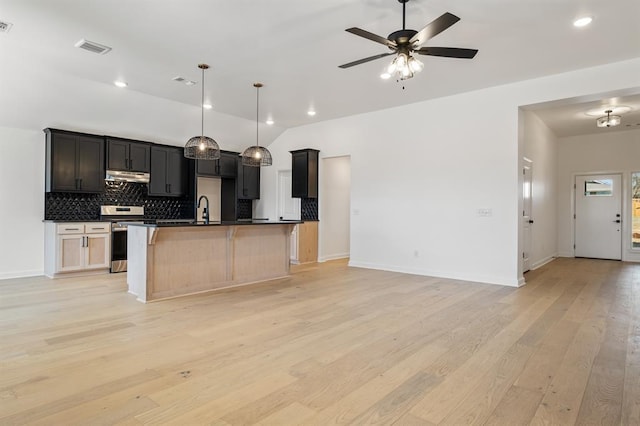 kitchen with tasteful backsplash, ceiling fan, light hardwood / wood-style flooring, stainless steel range oven, and an island with sink