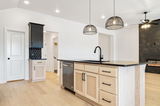 kitchen featuring dishwasher, sink, an island with sink, pendant lighting, and a tiled fireplace