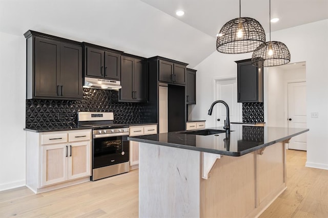 kitchen featuring light wood-type flooring, stainless steel appliances, vaulted ceiling, sink, and a center island with sink