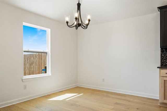 unfurnished dining area featuring light hardwood / wood-style floors and an inviting chandelier