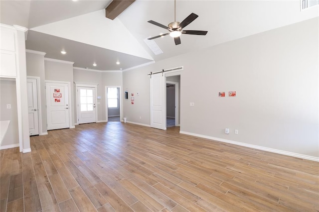 empty room with vaulted ceiling with beams, ceiling fan, a barn door, and light hardwood / wood-style flooring