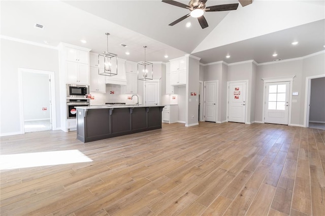 kitchen featuring white cabinetry, stainless steel oven, hanging light fixtures, and a center island with sink