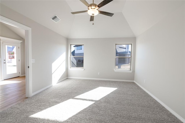 carpeted spare room with ceiling fan, a healthy amount of sunlight, and lofted ceiling