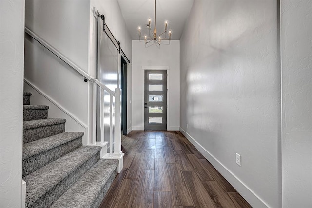 foyer entrance featuring a high ceiling, a barn door, dark hardwood / wood-style floors, and an inviting chandelier