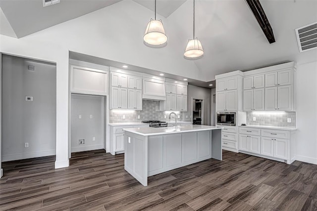 kitchen featuring hanging light fixtures, backsplash, white cabinetry, and stainless steel microwave