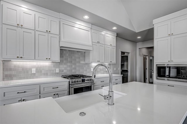 kitchen featuring vaulted ceiling, white cabinetry, high end stainless steel range oven, and black microwave