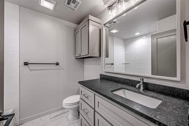 bathroom with a tile shower, vanity, and toilet