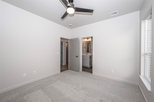 unfurnished bedroom featuring ceiling fan, light carpet, and ensuite bath