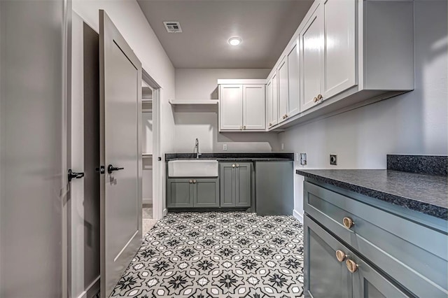 kitchen with white cabinets, stainless steel fridge, light tile patterned flooring, and sink