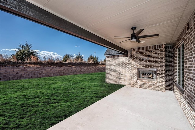 exterior space featuring an outdoor brick fireplace, ceiling fan, and a patio