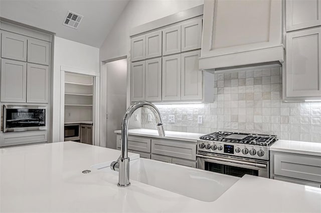 kitchen featuring appliances with stainless steel finishes, backsplash, vaulted ceiling, and sink