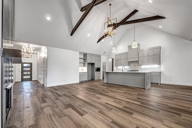 kitchen featuring pendant lighting, gray cabinetry, an island with sink, beamed ceiling, and dark hardwood / wood-style flooring