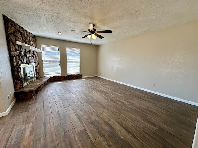 unfurnished living room featuring a textured ceiling, ceiling fan, wood-type flooring, and a fireplace