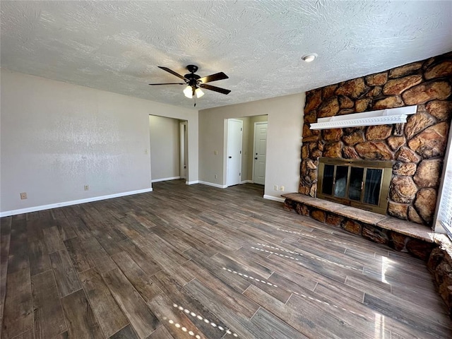 unfurnished living room with a stone fireplace, ceiling fan, hardwood / wood-style floors, and a textured ceiling