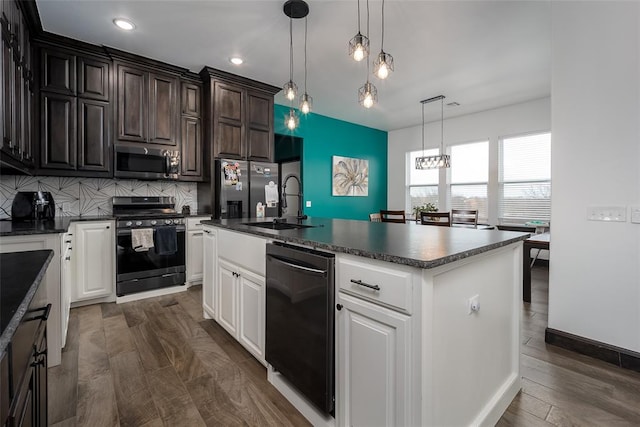 kitchen featuring dark wood-type flooring, white cabinets, an island with sink, and appliances with stainless steel finishes