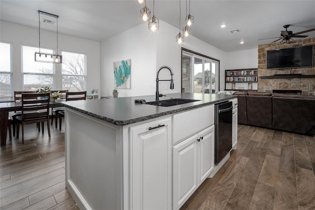 kitchen with sink, white cabinetry, a kitchen island with sink, and hanging light fixtures