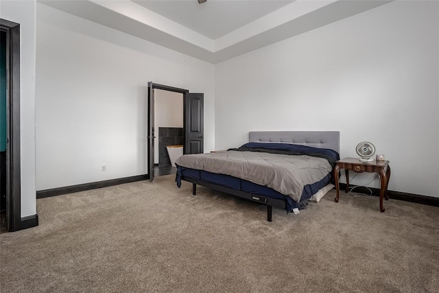 carpeted bedroom with a raised ceiling and ensuite bath