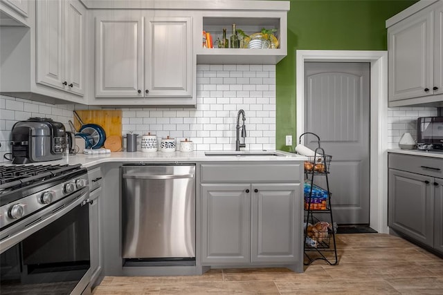 kitchen featuring white cabinets, sink, decorative backsplash, light wood-type flooring, and appliances with stainless steel finishes