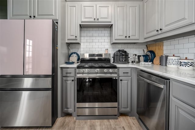 kitchen featuring tasteful backsplash, gray cabinets, light hardwood / wood-style flooring, and appliances with stainless steel finishes